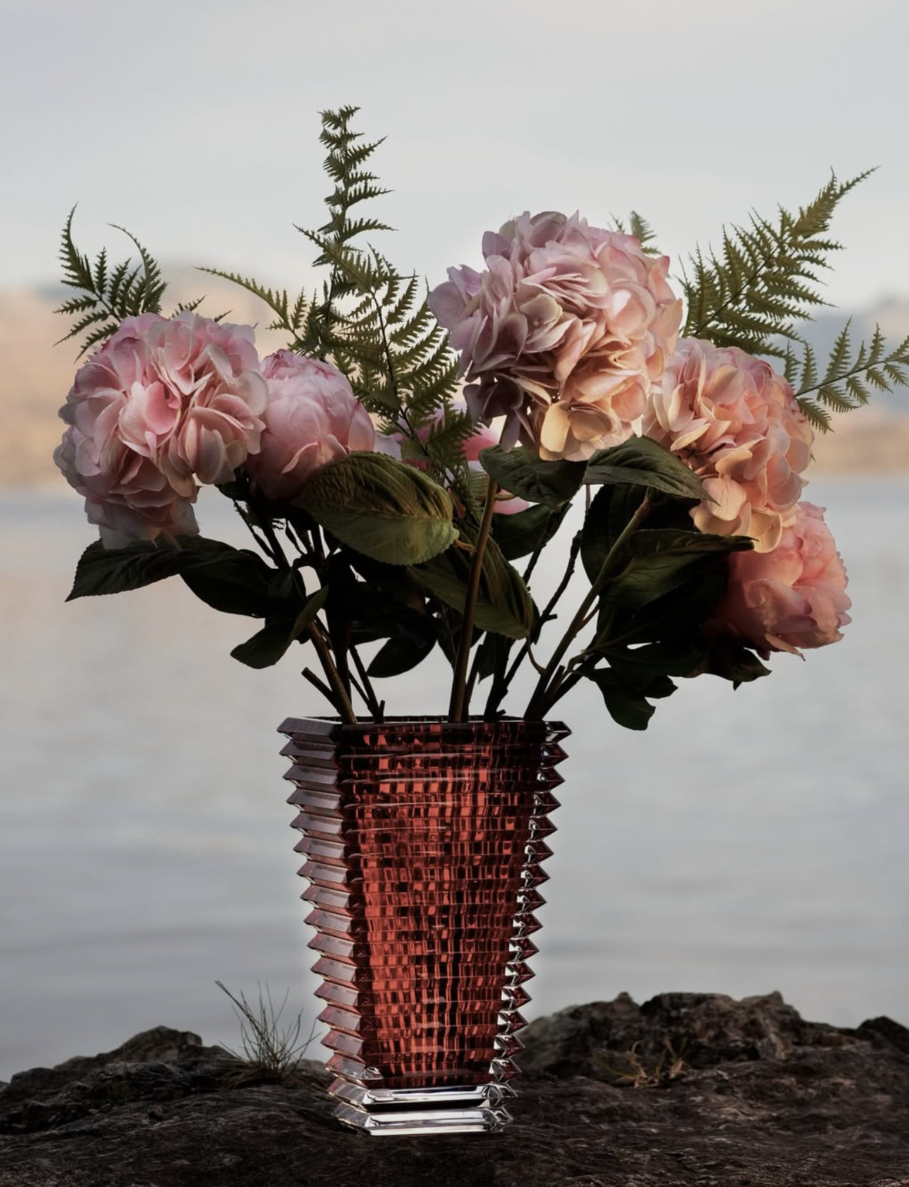 Sculptural crystal vase with peonies by the water — an ode to craft and light